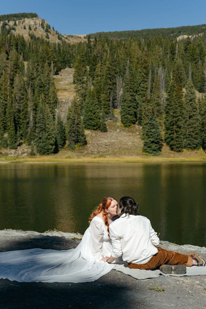 Couple kissing beside a mountain lake during their Crested Butte elopement, featuring scenic Colorado elopement photography and romantic lakeside wedding portraits.