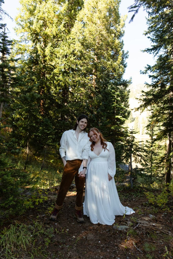 The bride and groom standing hand in hand and smiling at the camera with aspens all around them during their Crested Butte Elopement