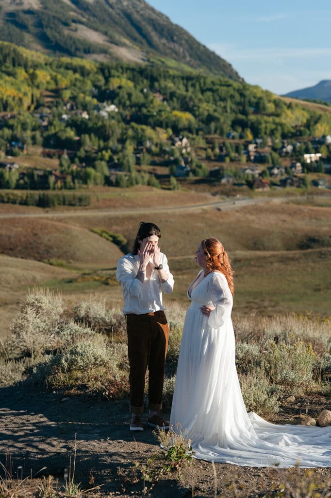 The groom wiping away tears while he reads his vows to his bride during sunset during their Crested Butte Elopement