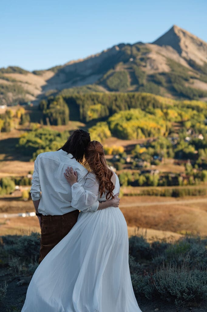 Couple stands with their heads pressed together looking at a sunset view of Mt. Crested Butte after saying their vows.
