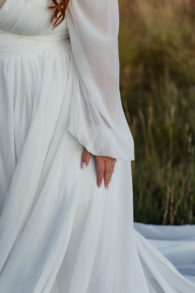 Close-up detail of a bride’s white elopement dress sleeve and wedding ring during a Crested Butte mountain elopement.