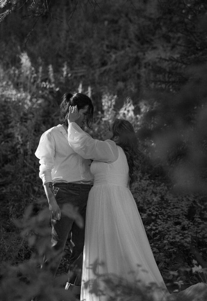 Intimate black and white portrait of a couple embracing in a forest during their Crested Butte elopement, surrounded by tall trees and soft natural light.