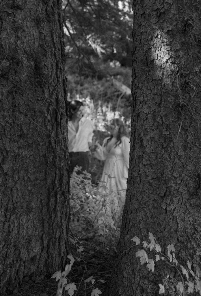 Artistic forest framing shot of a couple through two trees during their Crested Butte elopement, creating a moody and cinematic mountain feel.