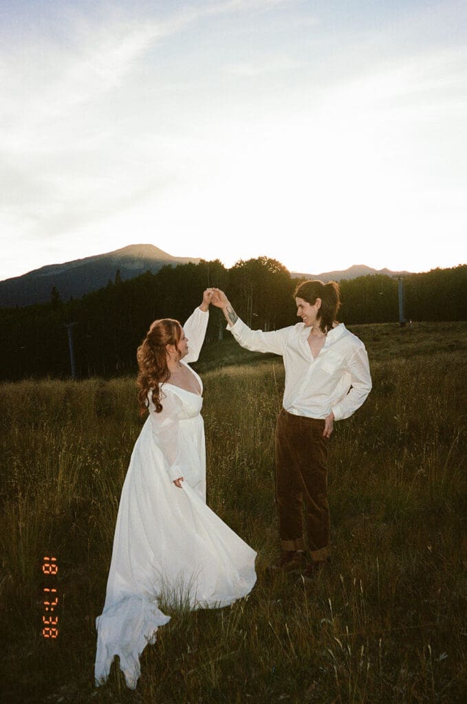 A flash film photo of a bride and groom spinning on top a mountain during sunset in Crested Butte.