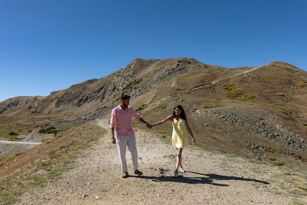 a couple holds hands and walks down one of the trails on the continental divide at Loveland Pass